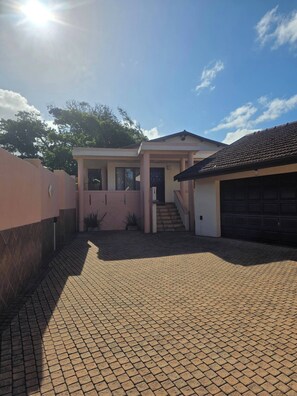 A residential property with a paved driveway, a garage, and a covered entrance. - Aloe Self Catering Two Bedroom Apartment Open Plan (Port Shepstone)