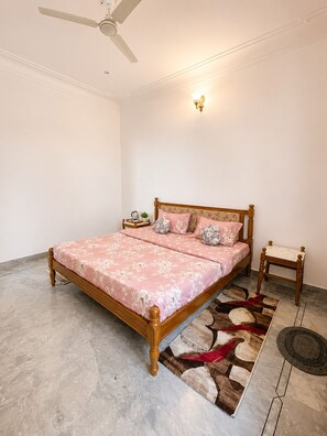 A bedroom with a bed, a nightstand, a lamp, and a ceiling fan.