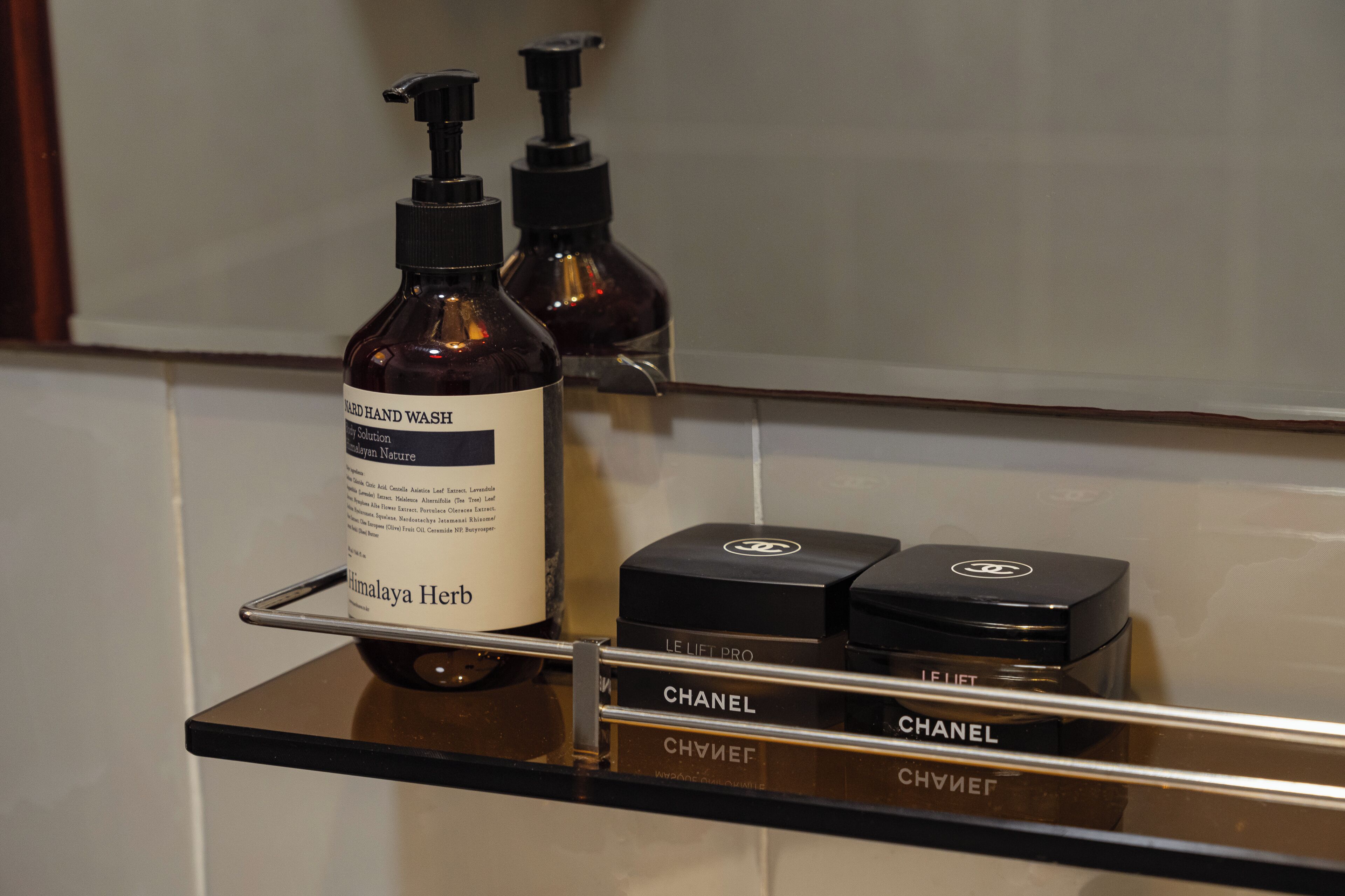 Une étagère de salle de bain avec un flacon de savon liquide et deux flacons de parfum.