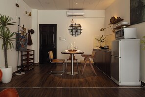 A compact kitchen with a dining area, a white refrigerator, and a wall-mounted air conditioner. - Saigon Cozy Home  (Ho Chi Minh City)