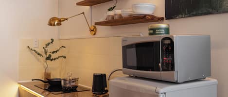 A kitchen with a built-in microwave, a coffee maker, and a plant.