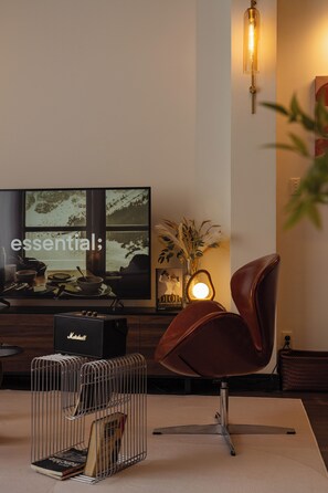 A modern living room with a flat-screen TV, a leather chair, a coffee table, and a decorative vase. - Saigon Cozy Home  (Ho Chi Minh City)