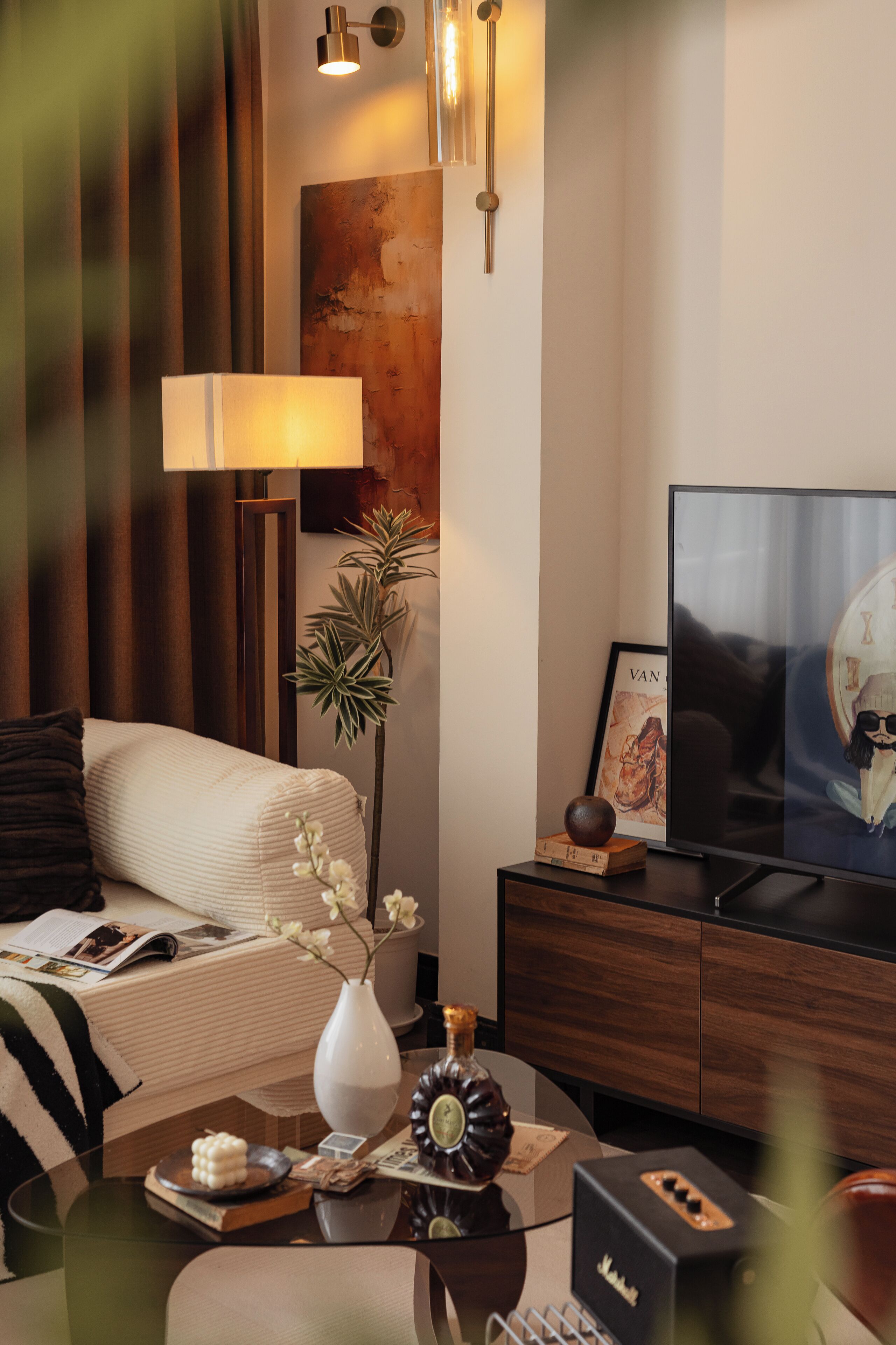 Un soggiorno moderno con un divano, un tavolino da caffè con oggetti decorativi, una TV e una lampada a parete.