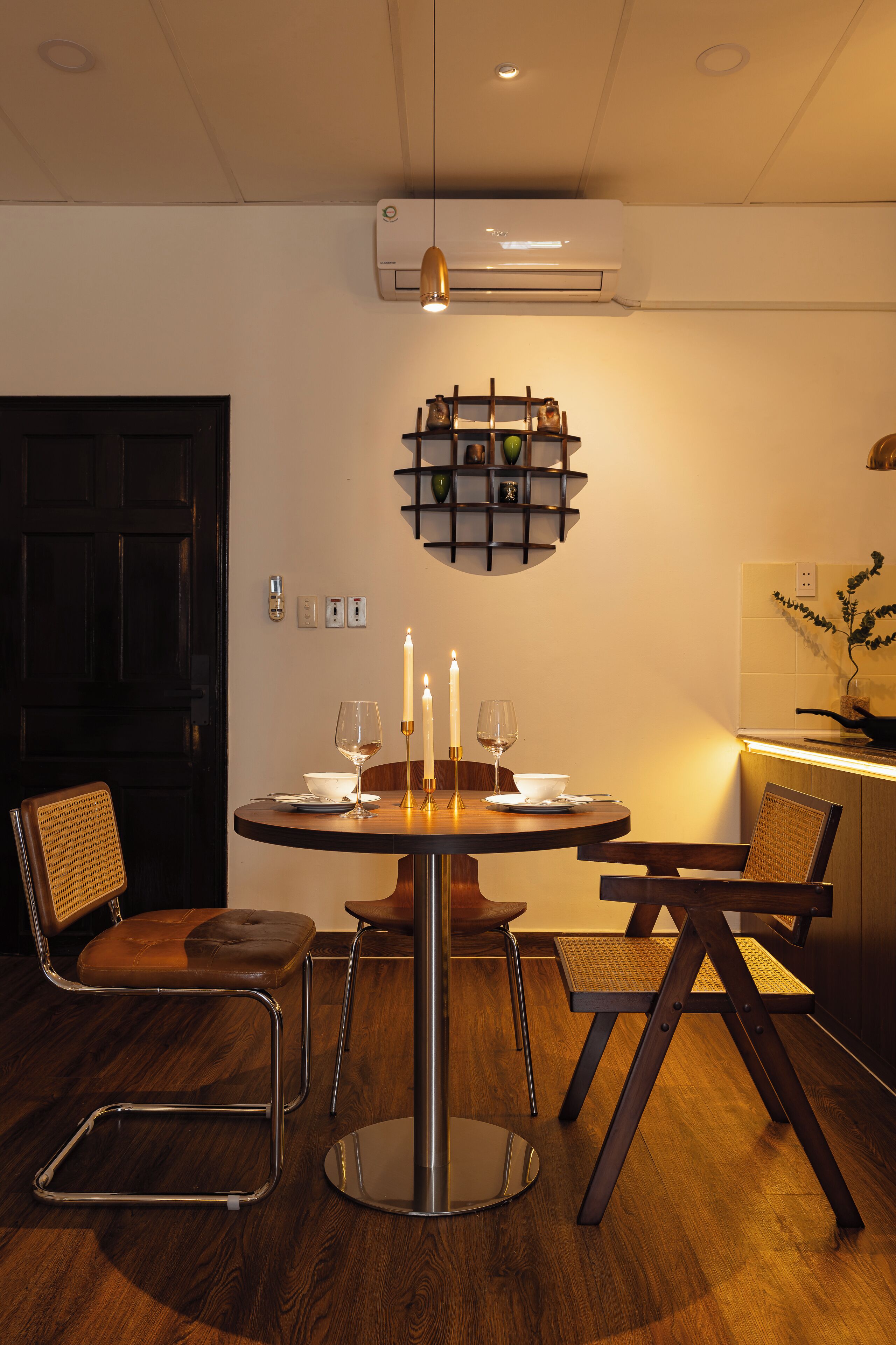 Een eethoek met een ronde tafel, stoelen en een wandplank met decoratieve objecten.