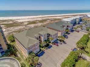 Ein Hotel direkt am Strand mit mehreren Gebäuden, einem Parkplatz und Blick auf Strand und Meer.