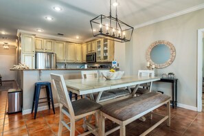 Una cocina moderna con armarios de madera, electrodomésticos de acero inoxidable y una zona de comedor con banco y taburetes.