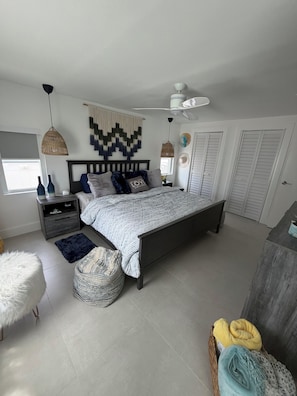 Ein modernes Schlafzimmer mit Bett, Nachttischen, einem Deckenventilator und einem Kleiderschrank.