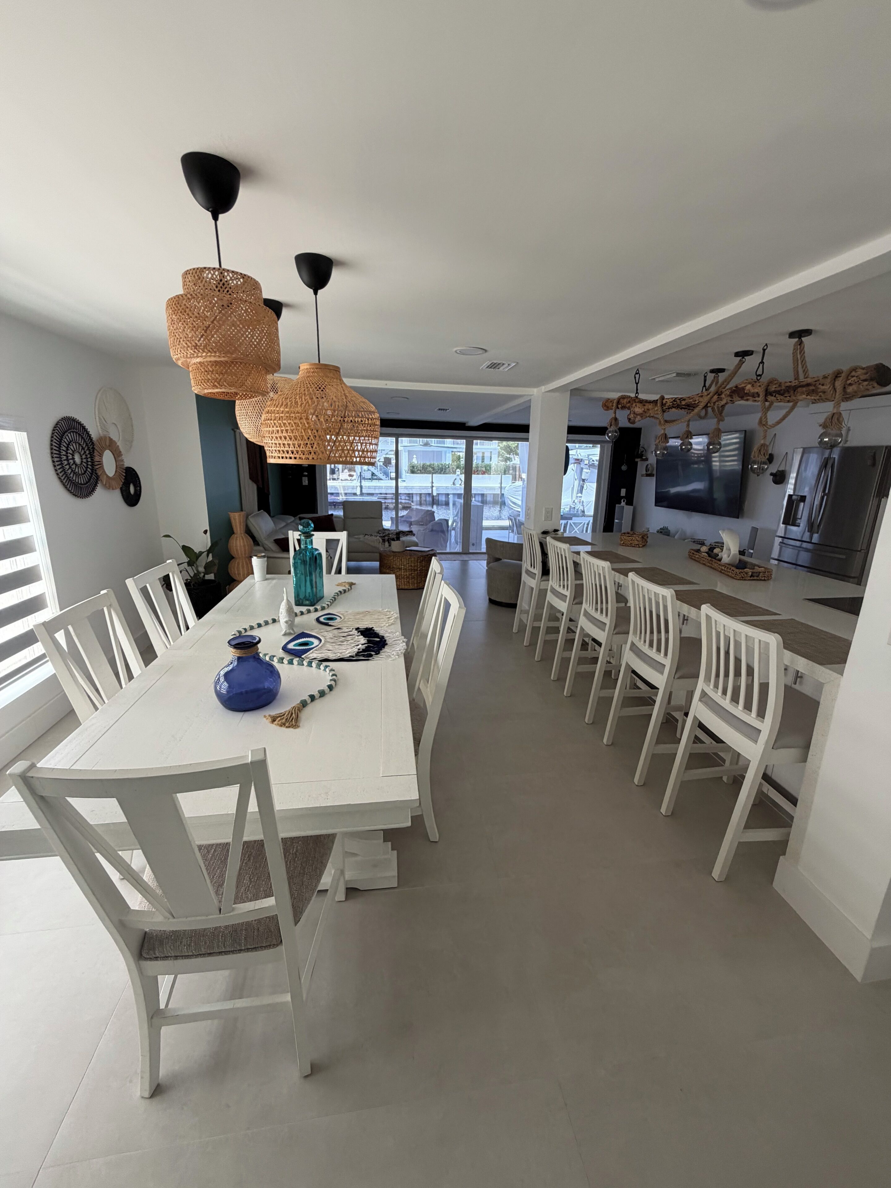 A modern kitchen with white cabinetry, a central island, and a dining area with white chairs.