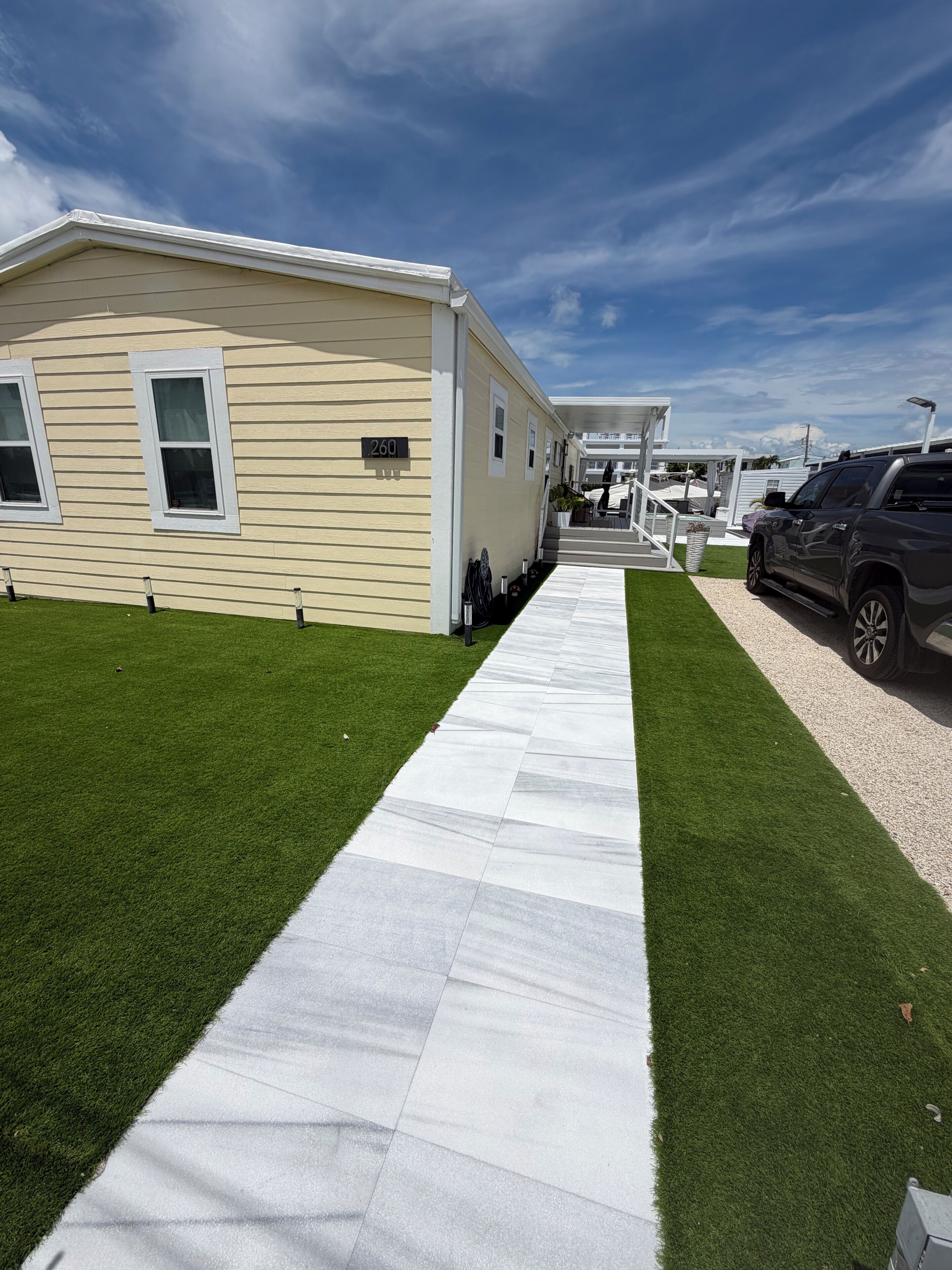 A mobile home with a paved walkway and a parked SUV.