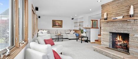 A modern living room with a fireplace, a sofa set, and a dining area.