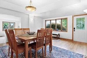 A dining room with a wooden table, chairs, and a chandelier.