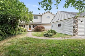 A two-story house with a stone pillar, a front porch, and a well-maintained lawn.