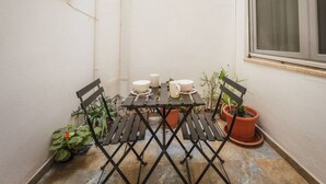 A small outdoor patio with a table set for two, surrounded by potted plants and a window. - Casa Due Balli 400-year Historic Valletta House (Valletta)
