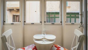 A room with a table and chairs, a window with a view of a building, and a door with a handle. - Casa Due Balli 400-year Historic Valletta House (Valletta)