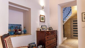 A hallway with a wooden dresser, a framed picture, and a staircase with a decorative railing. - Casa Due Balli 400-year Historic Valletta House (Valletta)