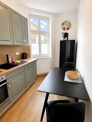 A modern kitchen with a black table, a coffee machine, and a window with blinds.