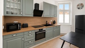 A modern kitchen with grey cabinets, a black microwave, and a black refrigerator. - Ahlbeck 'Agape 2-Room Apartment' for 2 to 4 Guests, 250 m from the Beach (Heringsdorf)