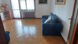 Una sala de estar con un sofá azul, un cuadro en la pared y un suelo estampado.