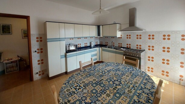 Una cocina con una mesa redonda, una estufa y un ventilador de techo.