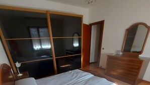 Un dormitorio con cama, cómoda, espejo y armario.