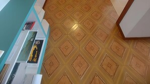 Un pasillo con piso estampado, una puerta al final y una mesita con una caja encima.