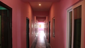 A corridor with doors on both sides, leading to rooms. - SSV Rooms (Tiruvannamalai)
