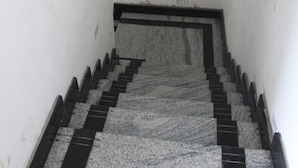 A narrow stairway with a black and white striped floor leading to a landing. - SSV Rooms (Tiruvannamalai)