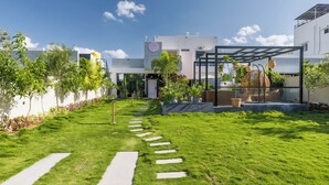 Un quartier résidentiel moderne doté d’une pelouse bien entretenue, d’un chemin menant à une entrée sécurisée et d’une serre.