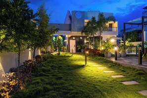 Un hotel moderno con un jardín cuidado, cielo despejado y entrada visible.
