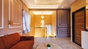 Un hall d’hôtel avec un canapé, une table basse, un lustre et une porte en bois.