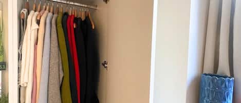 A closet with hanging clothes and shelves with folded items.