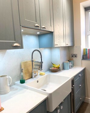A kitchen with a white sink, grey cabinets, and a wooden cutting board. - Beautiful and spacious 2 Double Bed, 2 Bath Garden Flat, Ealing, London, W5 (London)