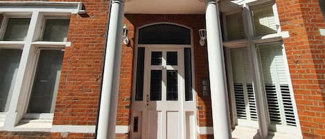 A two-story brick building with a white entrance and columns, featuring a number '51' above the door.