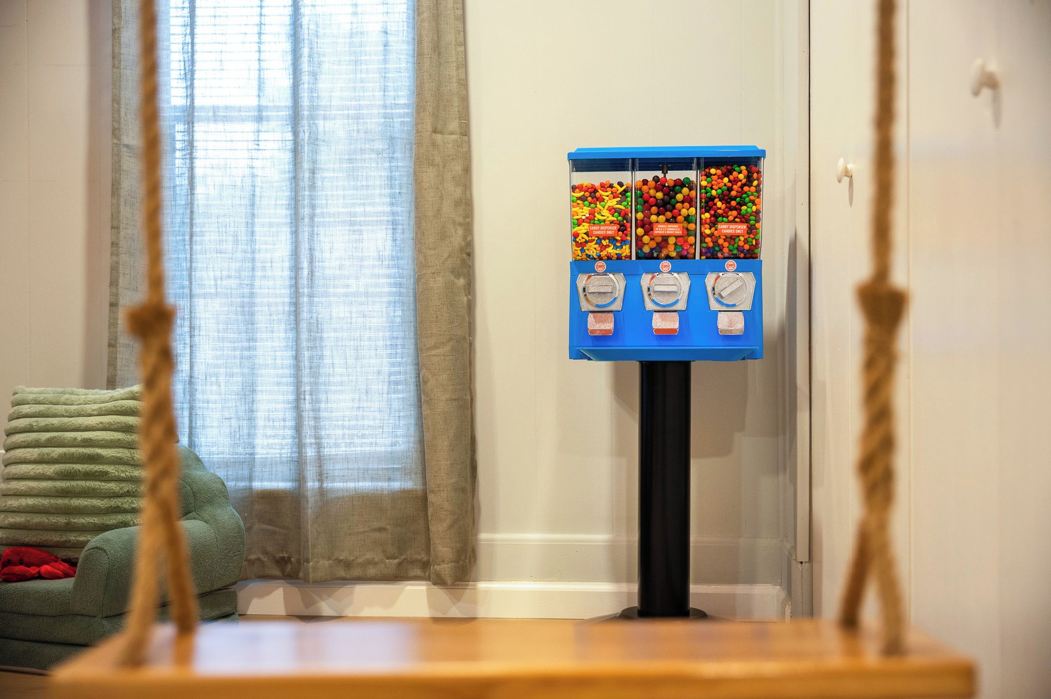 A room with a window, a green sofa, and a candy dispenser.
