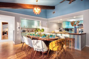 A modern kitchen with teal cabinets, a dining area with a round table, and a bar area with a blue vase. - Heated Pool • Hot Tub • Pickleball • Game Room (Seminole)