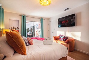 A hotel room with a bed, a TV mounted on the wall, and a view of the outside. - Heated Pool • Hot Tub • Pickleball • Game Room (Seminole)