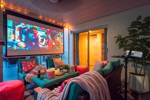 Un espace intérieur accueillant avec un grand écran, des sièges confortables, du pop-corn et un projecteur.
