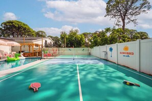 A pool area with a tennis court, lounge chairs, and a sign for 'SUNKISSED sea villa'. - Heated Pool • Hot Tub • Pickleball • Game Room (Seminole)