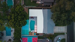 An aerial view of a residential property with a swimming pool, a tennis court, and a covered patio area. - Heated Pool • Hot Tub • Pickleball • Game Room (Seminole)