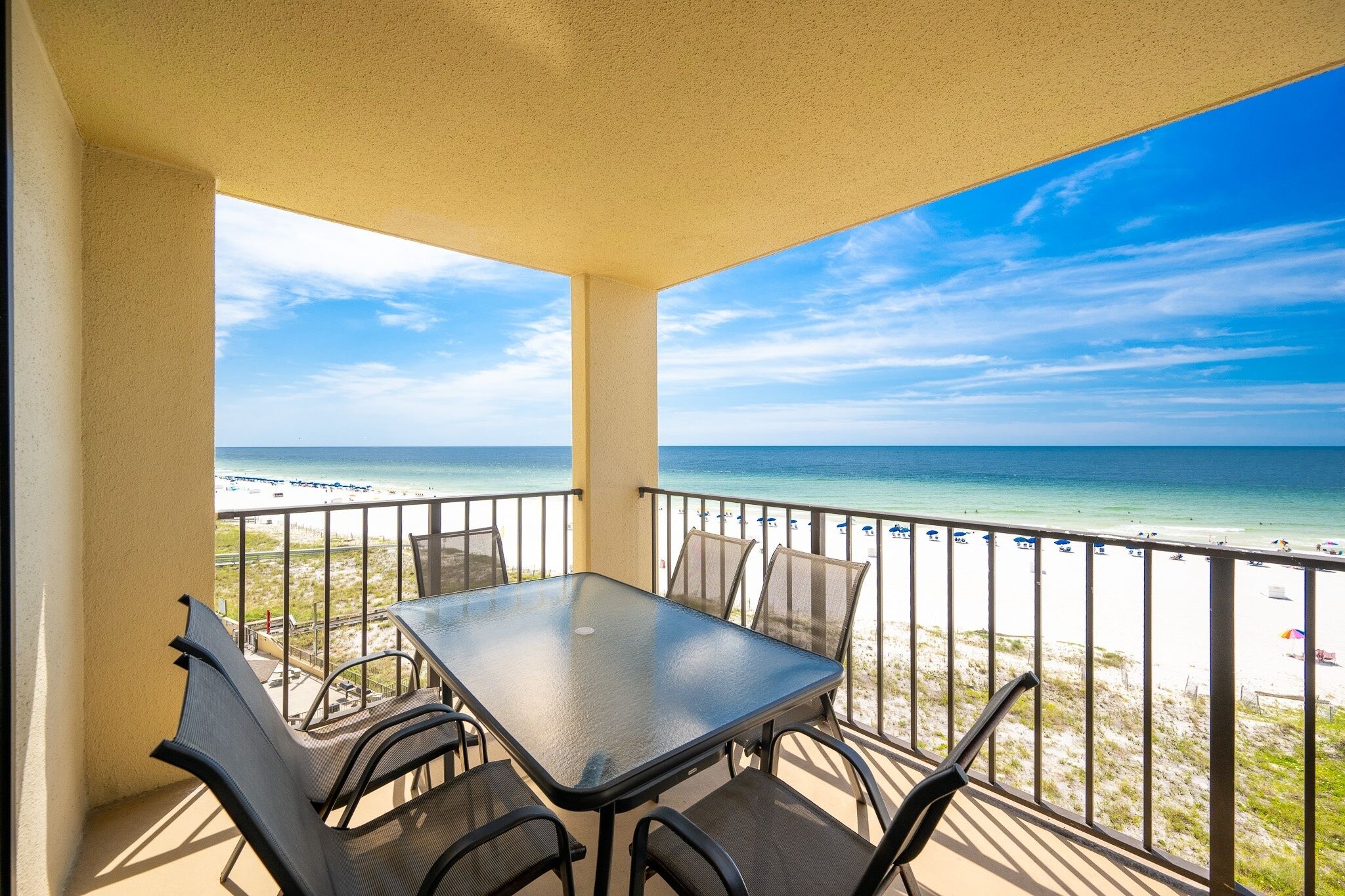 Ein Balkon mit Tisch und Stühlen mit Blick auf einen Strand.
