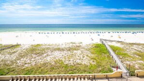 A beach with a boardwalk leading to the water, sandy beach, and umbrellas. - Phoenix Iii 3056 2 Bedroom Condo (Orange Beach)