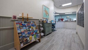 Un espace d’accueil avec un panneau d’affichage où sont présentés divers magazines, ainsi qu’un panneau indiquant l’emplacement des alarmes incendie sur le mur.