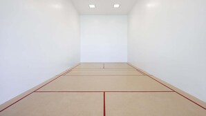 Une pièce spacieuse avec un plafond haut, des murs blancs et un plancher en bois, des lignes rouges délimitant l’aire de jeu.