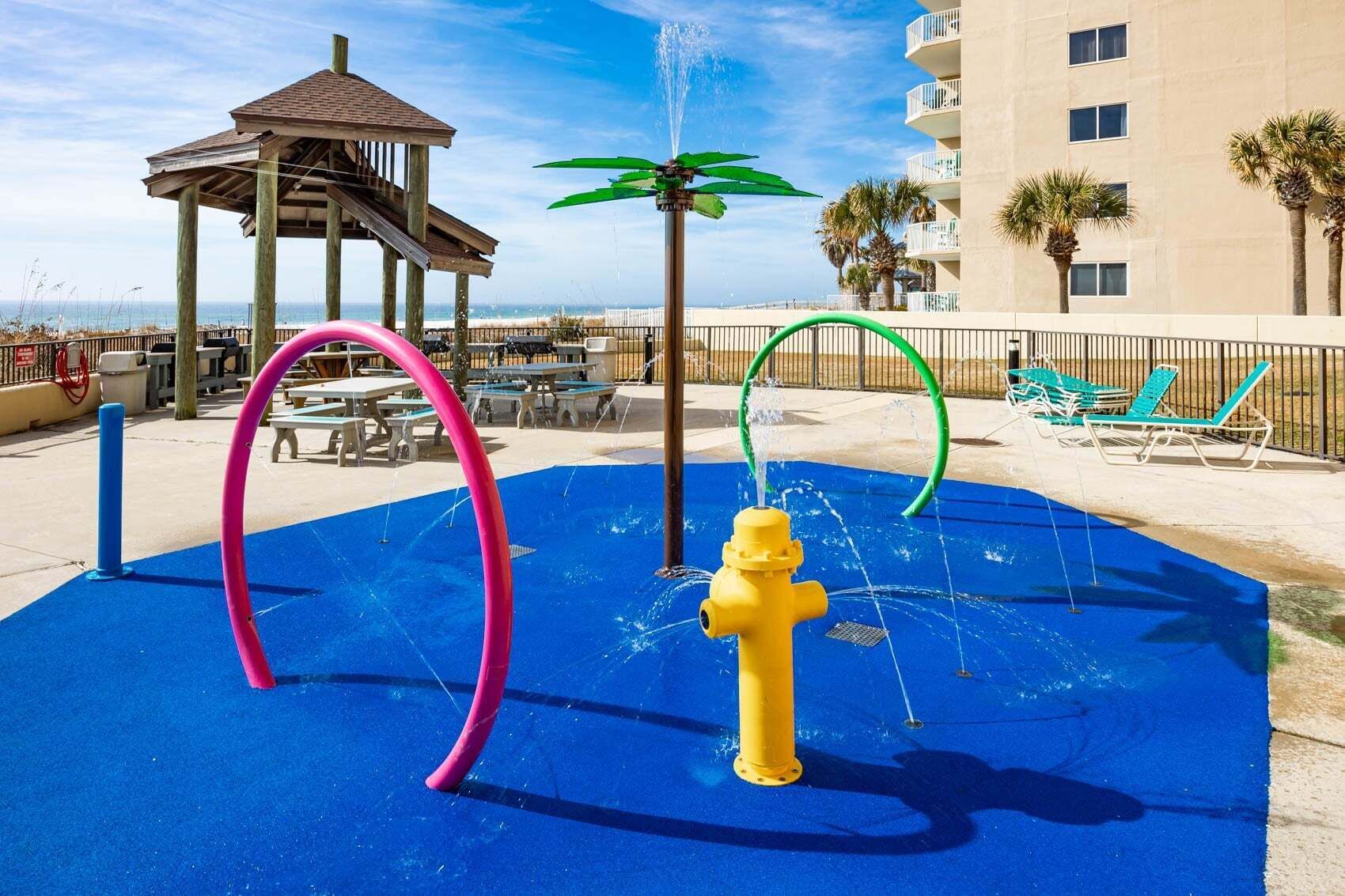 Un espace de jeux aquatiques avec une surface bleue, un hydrant jaune et un kiosque.