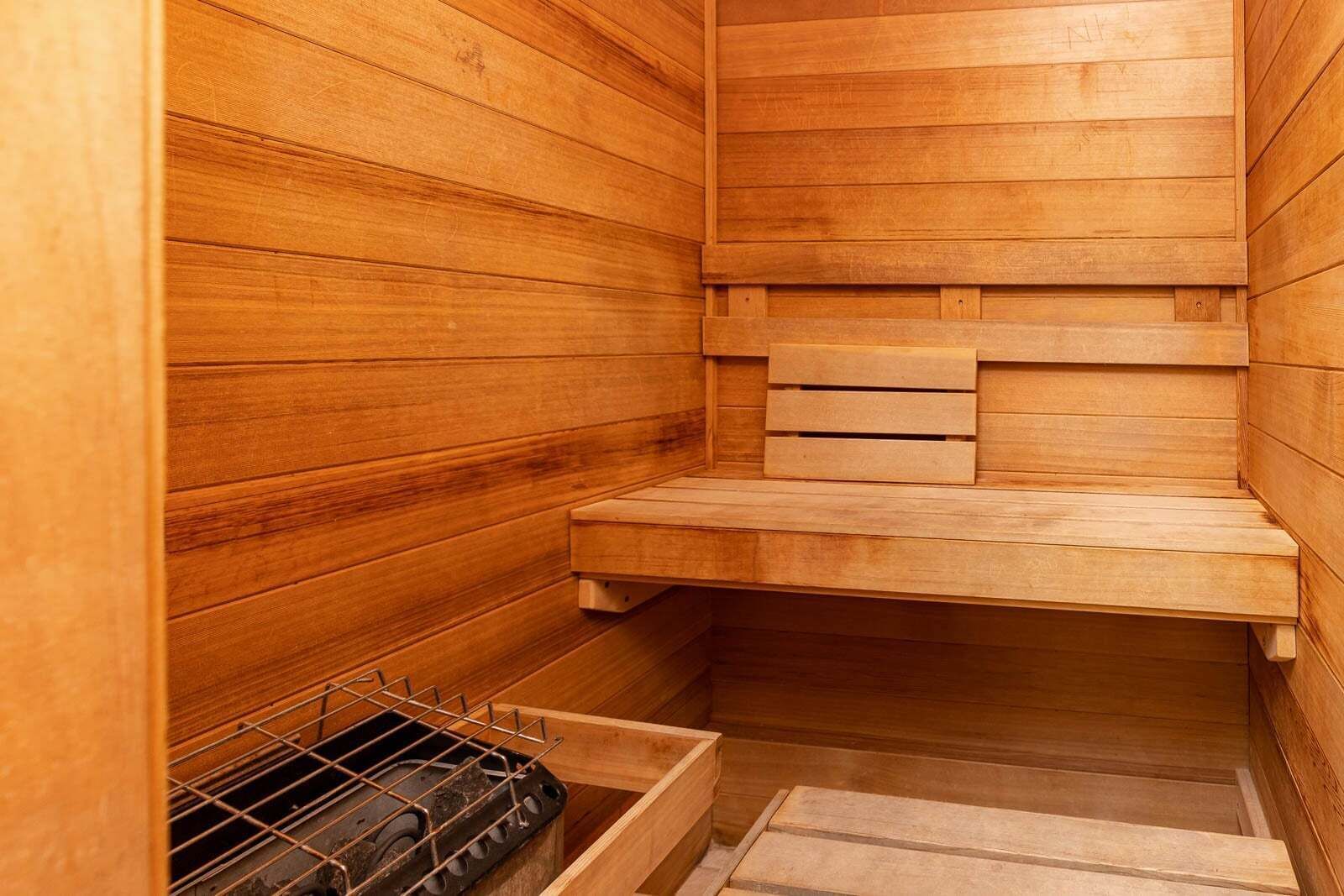 Un sauna en bois, doté de bancs et d’une étagère en métal.