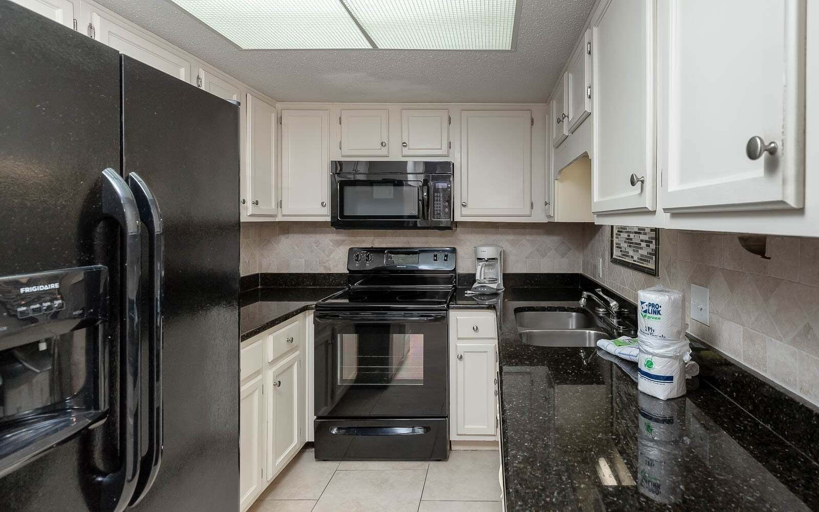 A compact kitchen with a refrigerator, microwave, stove, oven, and a coffee maker.