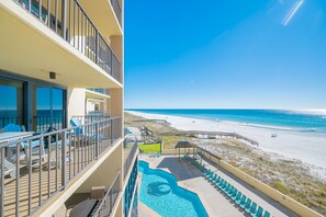 Ein Hotelbalkon mit Pool, Liegestühlen und Blick auf den Strand.