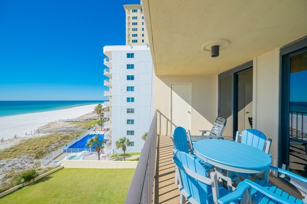 A balcony with a table and chairs overlooking a beach and a pool. - Phoenix I 1043 2 Bedroom Condo (Orange Beach)