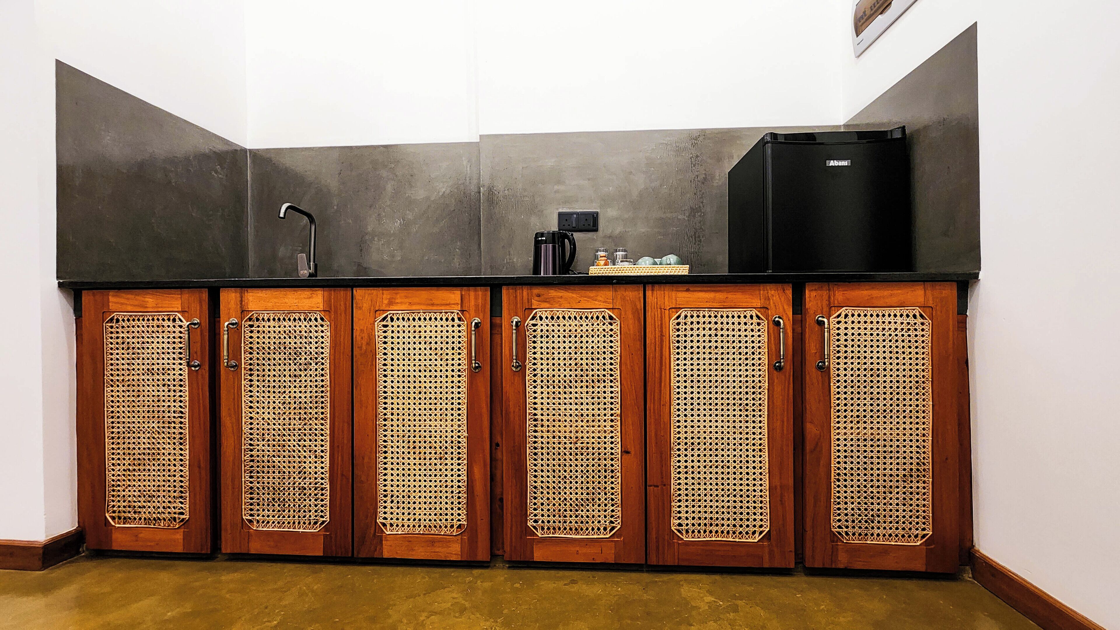 A kitchenette with a black refrigerator, a coffee maker, and a sink.