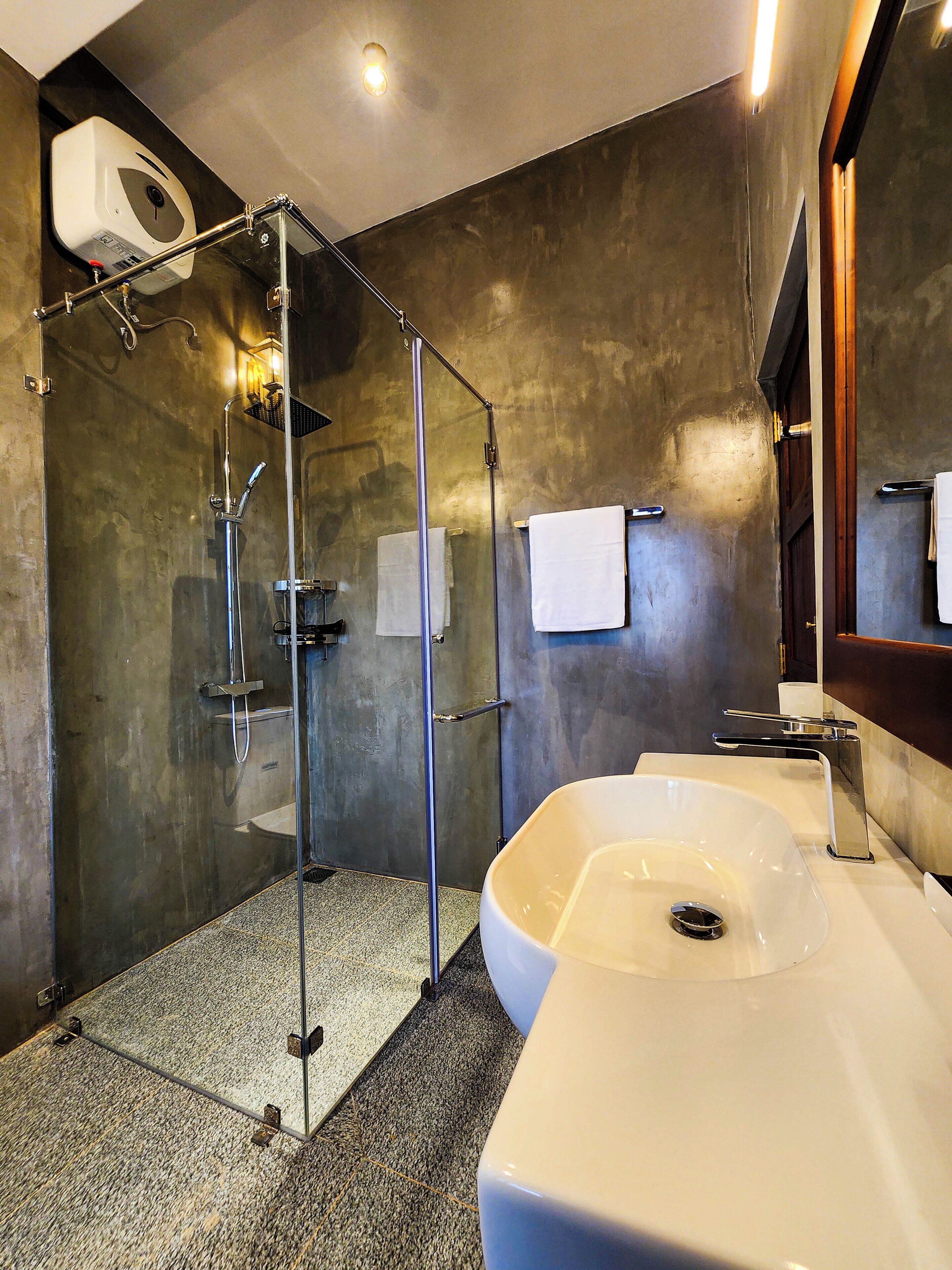 Un bagno moderno con cabina doccia in vetro, un ampio lavandino bianco e un porta asciugamani.